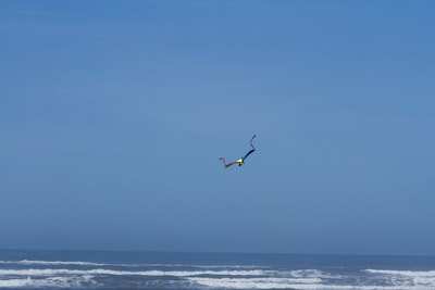Photograph of a lone kite flying high above the Pacific Ocean.